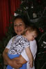 Vangie holds a sleeping Nora with the Christmas tree behind them